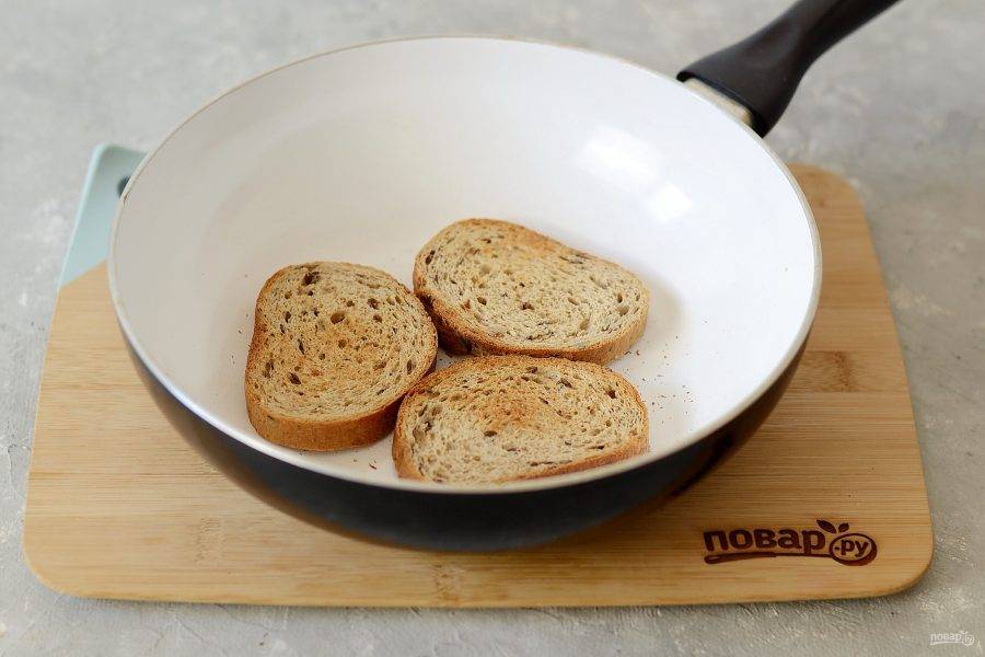 Подсушите ломтики хлеба на сухой сковороде до хрустящей корочки.