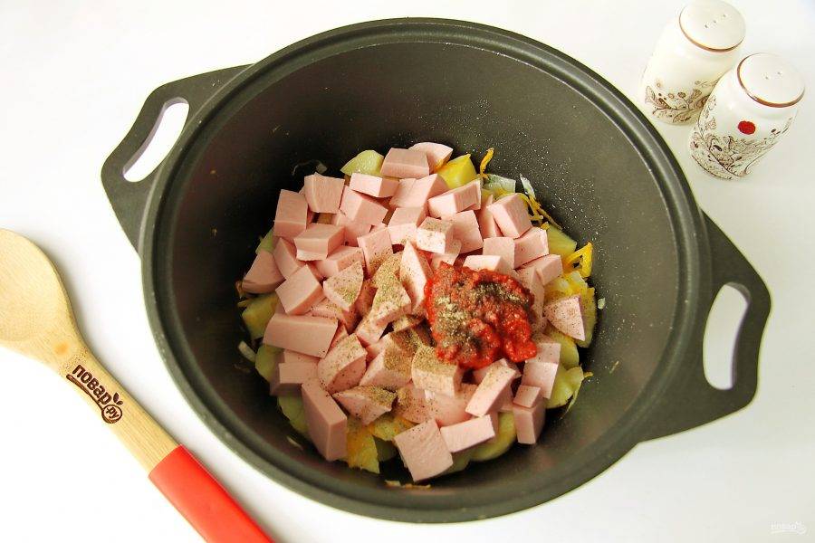 Добавьте нарезанную крупными кубиками колбасу, томатную пасту, соль и перец по вкусу.