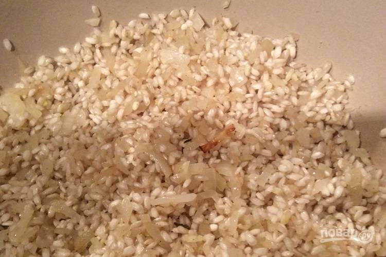 2.	Разогрейте растительное масло в отдельной кастрюле, добавьте лук и готовьте 10 минут, пока он не станет полупрозрачным, затем добавьте чеснок и рис, готовьте до слегка коричневого цвета риса.