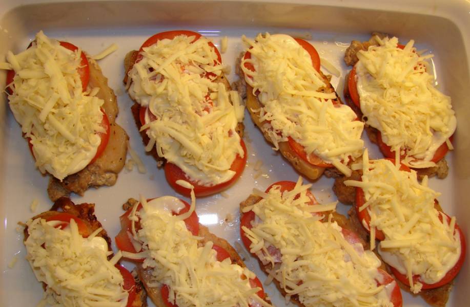 Переложите мясо на противень, сверху выложите кружочки помидоров. Нанесите слой майонеза и присыпьте отбивные тертым сыром. Запекайте 10 минут в духовке, температура 200 градусов.