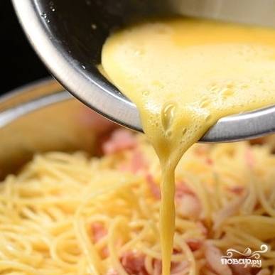 6. Яйца взбейте вилочкой или венчиком. Перемешайте спагетти с беконом и, продолжая помешивать, добавьте взбитые яйца.