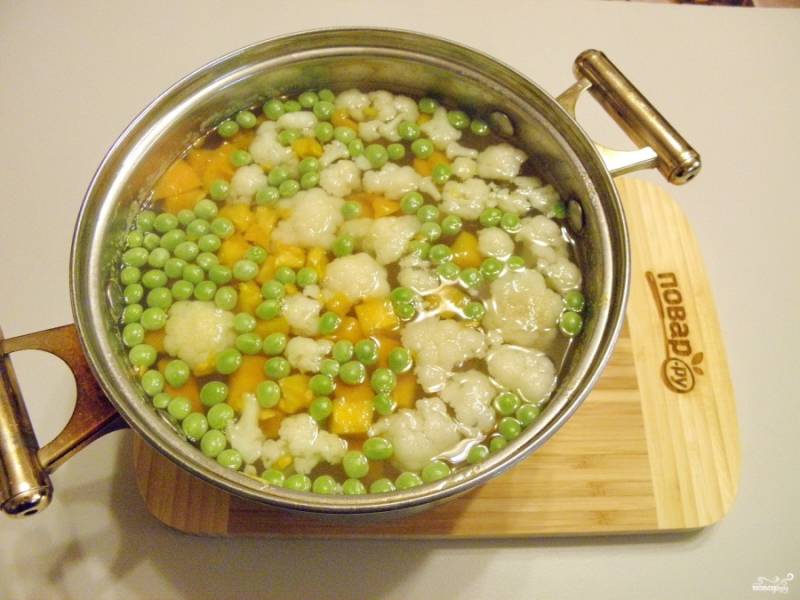 Спустя 15 минут добавьте в суп цветную капусту, горошек и помидор. Проварите еще 10 минут.