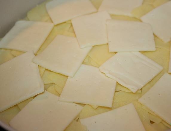 3. Дальше - слой тонких картофельных пластинок. Половину сыра режем ломтиками  и выкладываем поверх картошки. Остаток трем на терке - будем посыпать блюдо сверху. 