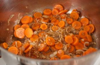 Добавляем морковь к луку, жарим еще пару минут. Затем добавляем курицу и вливаем бульон. Доведя до кипения, варим 40 минут. Затем извлекаем курицу из бульона и отделяем мясо от костей. Возвращаем курицу назад в суп.
