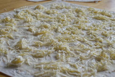 1. На один лаваш намазываем половину от всего количества сметаны. Выкладываем мелко натертый сыр. Накрываем, чуть вдавливая, вторым листом лаваша, чтобы масса склеилась.