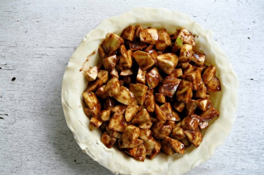 6.	Тесто раскатайте по форме для выпечки, выложите тесто и сформируйте бортики, чтобы они свисали с формы. Внутрь уложите яблочную начинку.
