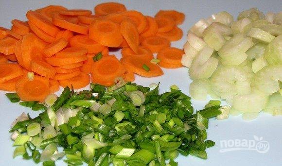 Вымойте зеленый лук, морковь и сельдерей. Очистите морковку и стебли сельдерея. Нарежьте их мелкими кусочками, лук измельчите ножом. 