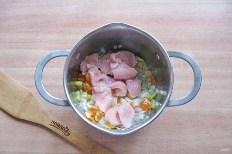 После куриное филе помойте, нарежьте небольшими кусочками и добавьте в кастрюлю с овощами. Готовьте овощи с курицей еще 7-8 минут.