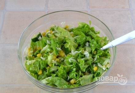 Переложите листья салата, огурцы и капусту в стеклянную посуду. Откройте банку консервированной кукурузы и слейте с нее жидкость. Выложите кукурузу к остальным ингредиентам. Полейте салат оливковым маслом и посолите. 