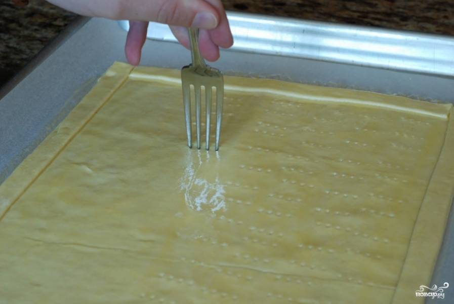 Поскольку тесто - слоеное, его нужно наколоть вилочкой практически по всей площади. Это делается для того, чтобы тесто не надувалось при запекании.