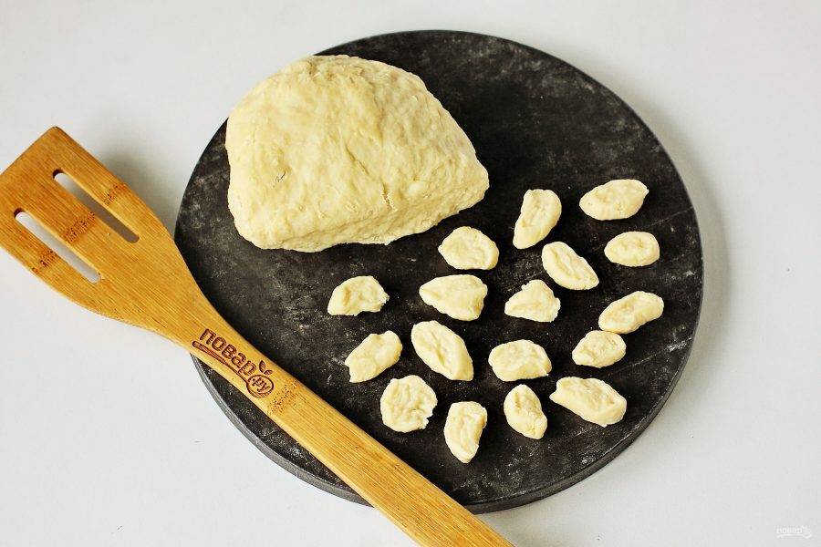 Отрежьте от теста кусок, раскатайте его колбаской и нарежьте небольшими кусочками. Размер кусочков зависит от желаемого размера готовых галушек.