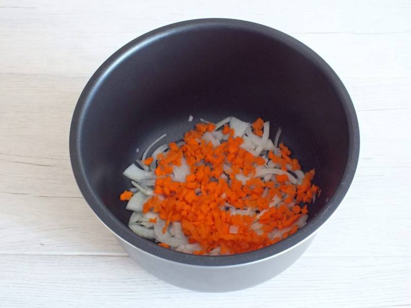 В чаше мультиварки разогрейте растительное масло, добавьте нарезанный четверть кольцами лук и мелко нарезанную морковь. Обжаривайте в режиме "Выпечка" в течение 10 минут, периодически помешивая.