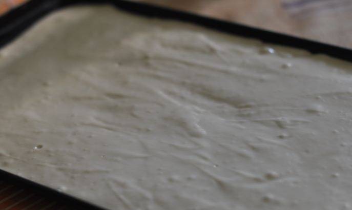 Смазываем противень растительным маслом и выкладываем на него приготовленное тесто, равномерно его распределяем по противню.