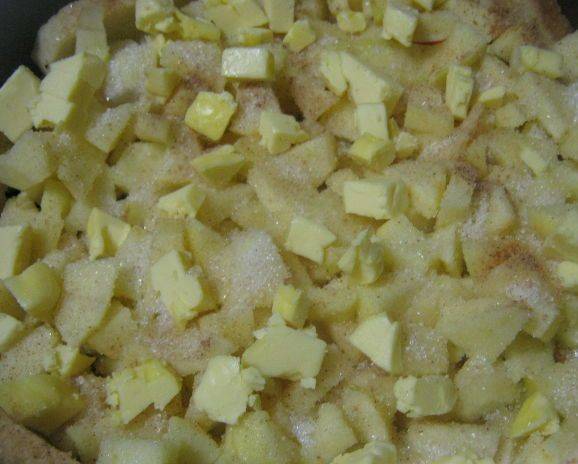 7. Выкладываем кусочки яблок. Сливочное масло режем кубиками и пересыпаем с яблоками. 