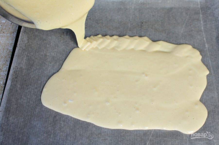 Противень покрываем пекарской бумагой и смазываем ее сливочным маслом. Выливаем бисквитное тесто и распределяем равномерным слоем. Отправляем в разогретую духовку. Выпекаем около 20 минут, при температуре 180 градусов. 