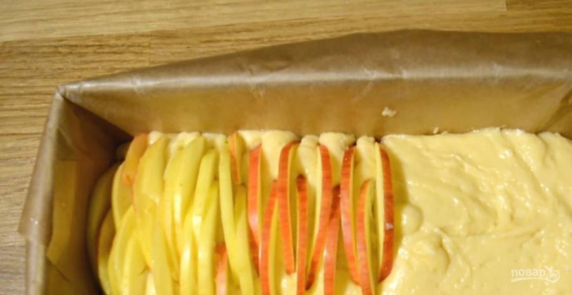 3. Выложите тесто в покрытую пергаментом форму. Яблоки помойте и очистите от сердцевины. Нарежьте яблоки тонкими пластинками и установите плотно друг к другу в тесте.
