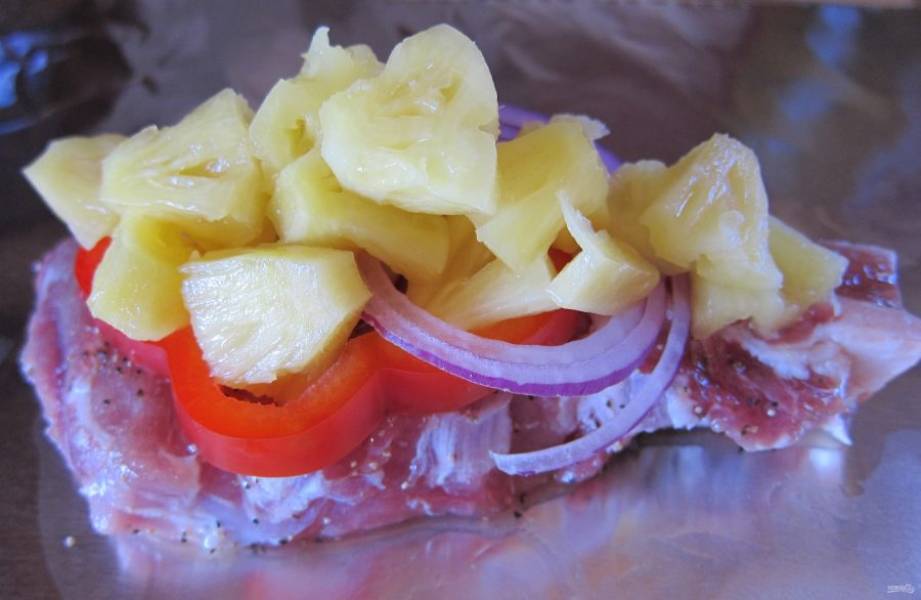 Подготовьте 4 кусочка фольги. На каждый положите по кусочку мяса, посолите, поперчите. Выложите по паре колечек лука, колечко перца и кусочки ананаса на каждую порцию.