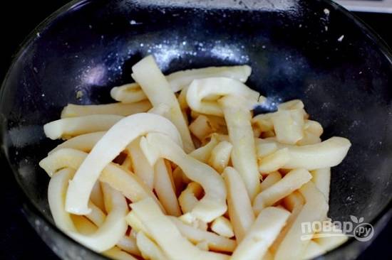 Перекладываем кальмаров в миску, добавляем к ним измельченный чеснок, уксус и оливковое масло. Перемешиваем и отправляем в холодильник часа на 2, пусть маринуются.
