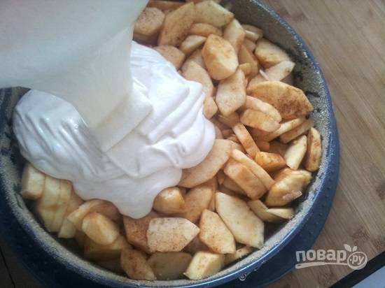 Форму для выпечки торта смажем маслом и посыпаем молотыми сухарями. Выкладываем яблоки и заливаем тестом.