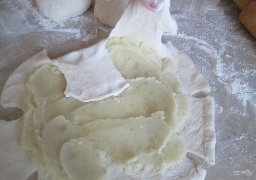 8.	Несколько ложек ранее приготовленного картофельного пюре выкладываю по центру лепешки и размазываю, затем оттягиваю каждый край и загибаю к центру.