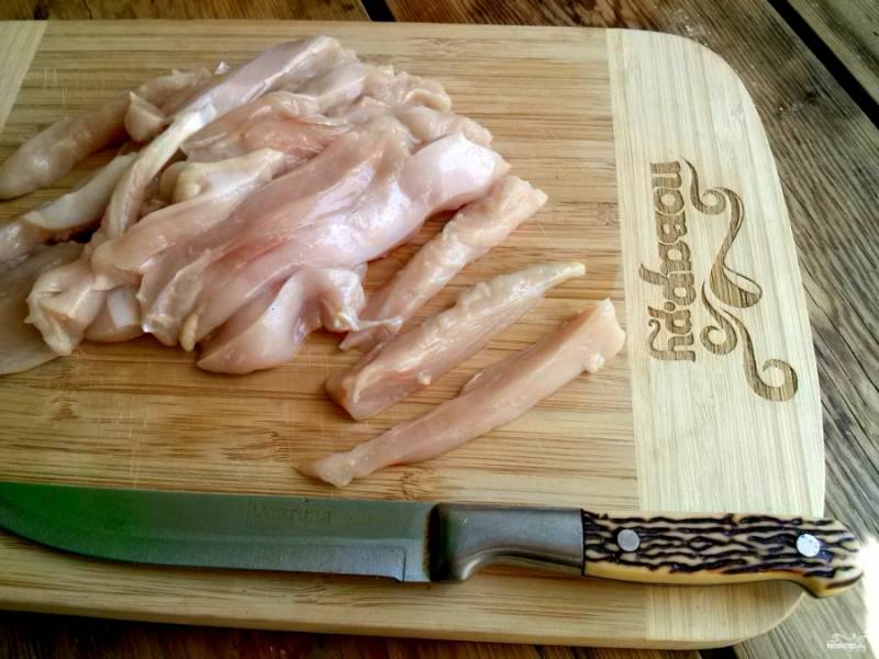 Куриное филе (или грудку) разрежьте сначала вдоль на три кусочка, а затем на тонкие полоски.