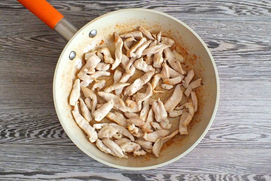 В сковороде разогрейте растительное масло. Обжарьте до румяной корочки нарезанное куриное филе. После снимите с огня и охладите.