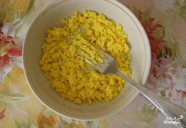 В это время сварите яйца в крутую. Затем отделите желток от белка. Желток раскрошите вилочкой, а белок натрите на мелкой терке.