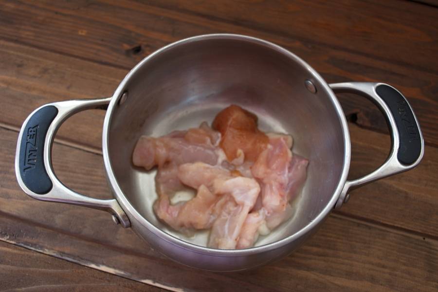 Куриное мясо нарезать небольшими кусочками. Уложить в кастрюлю. Лучше использовать филе или мясо без шкурки.