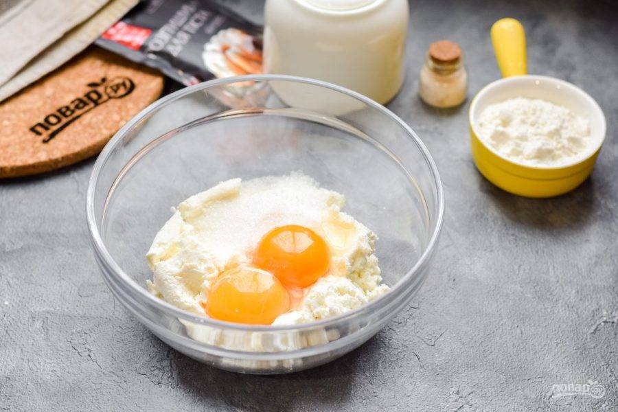 Переложите маскарпоне в миску, добавьте сахар, два яйца и мягкое масло.