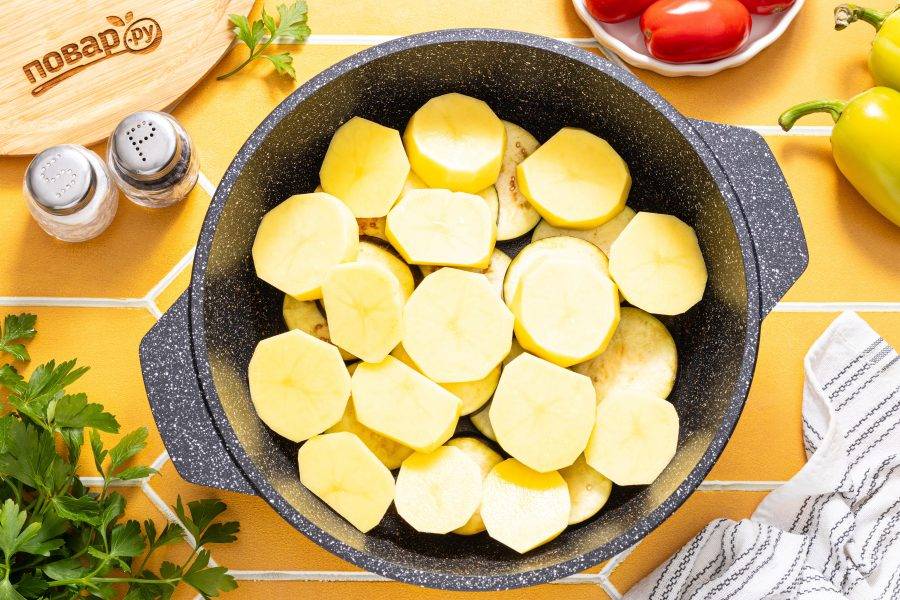 Картофель очистите от кожуры, нарежьте крупными ломтиками. Добавьте к баклажанам.