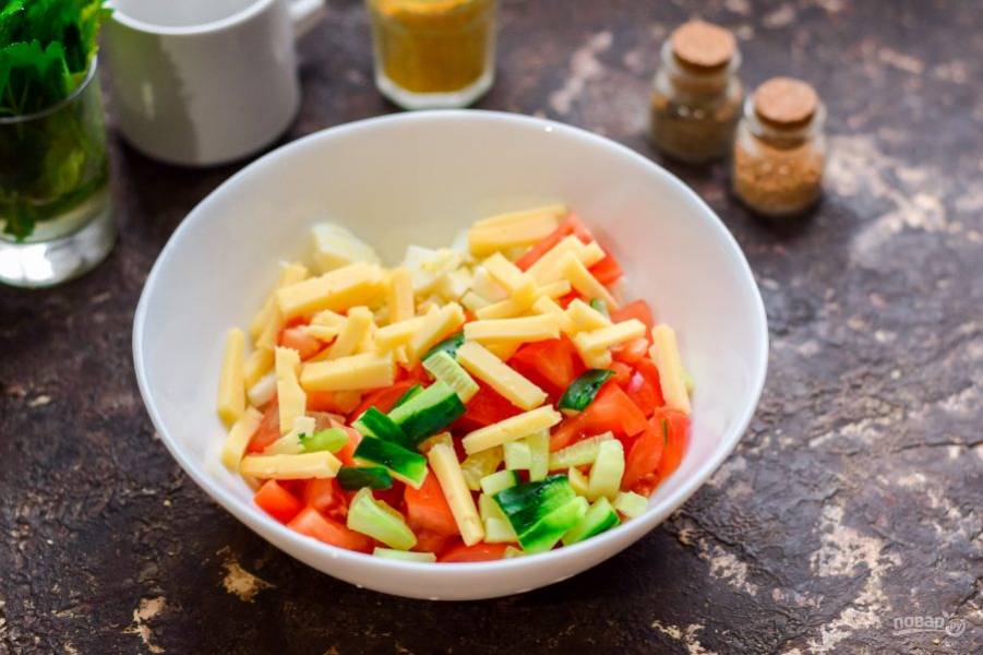 Переложите помидор в миску с яйцами. Нарежьте полосками свежий огурчик и твердый сыр, добавьте ингредиенты в салат.