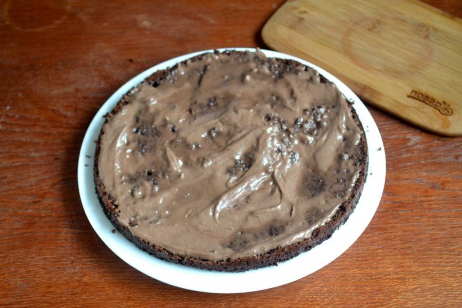 Начинайте собирать торт. Готовый шоколадный корж разрежьте вдоль пополам. Нижнюю часть обильно смажьте кремом.