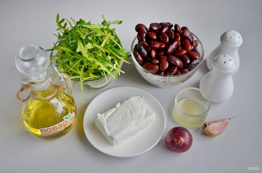 1. Подготовьте продукты для салата: с фасоли сцедите рассол, вымойте рукколу, очистите лук и чеснок, с половинки небольшого лимона выжмите сок.