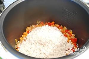 В чашу мультиварки налить растительное масло. Добавить промытый рис, нарезанные овощи - болгарский перец, морковь, лук. Добавить зеленый горошек и кукурузу. Количество горошка и кукурузы регулируйте по своему вкусу.