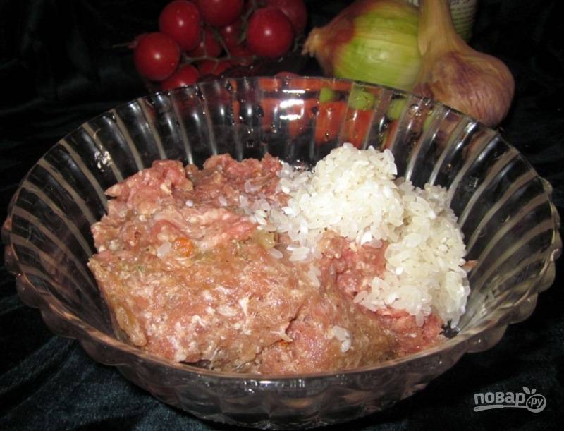 Фарш смешайте с промытым рисом, измельчённым луком и зубчиком чеснока. Добавьте соль и перец по вкусу. Тщательно перемешайте.