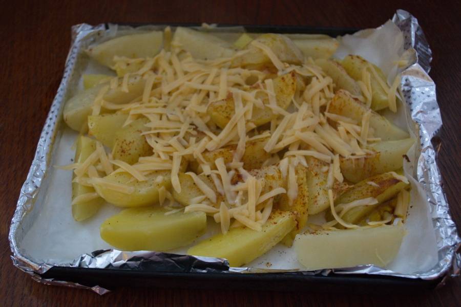 Достаньте картофель из духовки. Посыпьте натертым сыром.