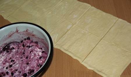 Творог, ягоды и сахар положить в глубокую тарелку и хорошо перемешать. Тесто нарезать на квадратики.