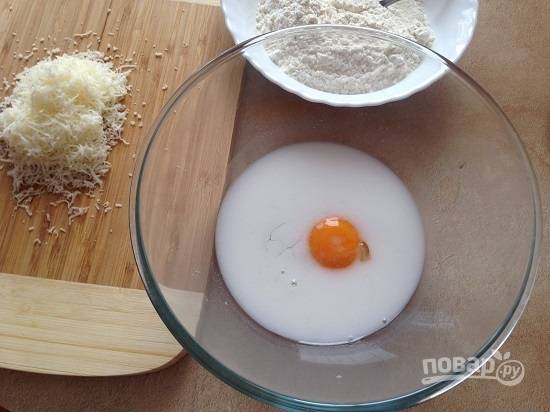 4. Твердый сыр натираем на мелкой терке. В миске взбиваем-размешиваем яйцо с молоком.