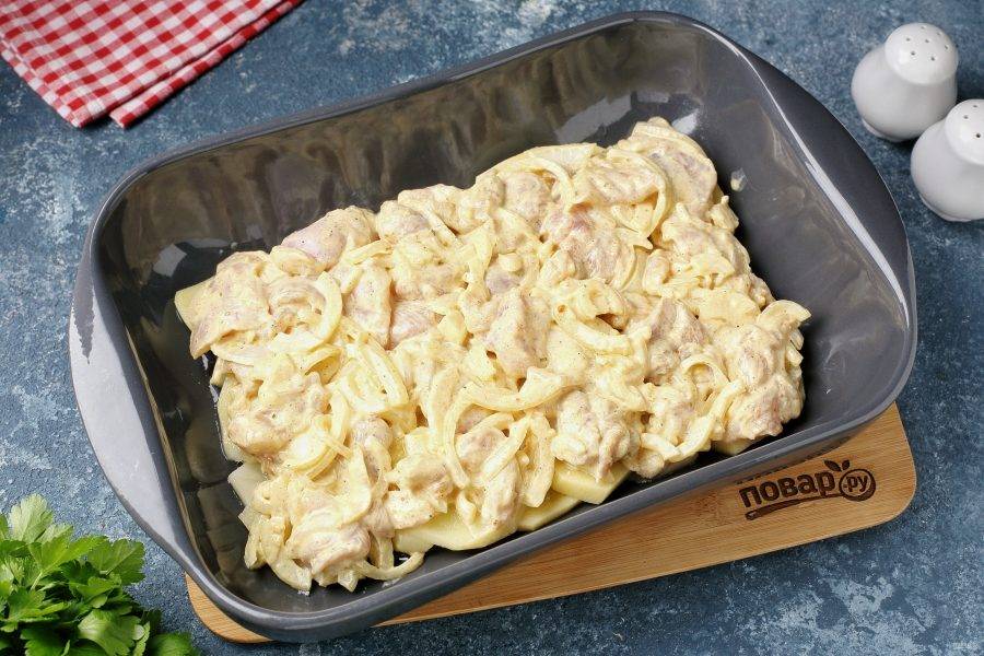 На картофель выложите маринованные куриные бёдра с луком.