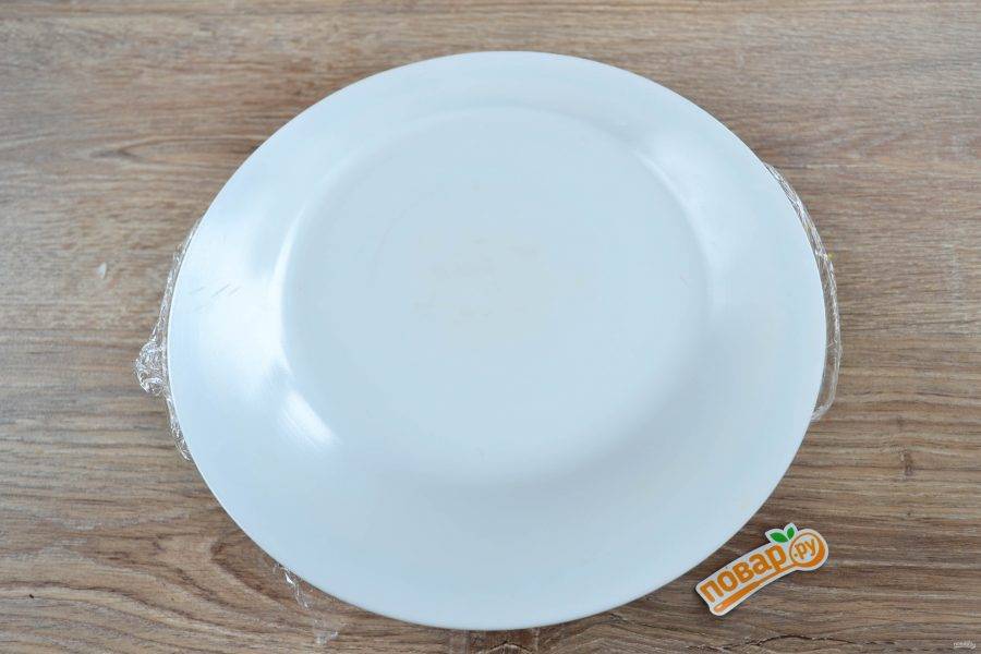 Накройте все плоской тарелкой и аккуратно переверните миску с салатом, чтобы грибы оказались сверху.
