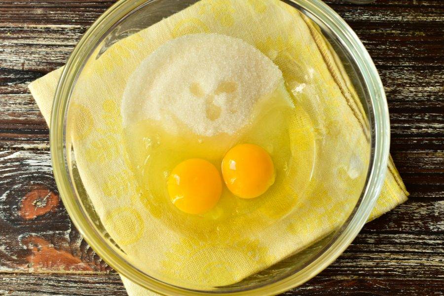 В миску вбейте куриные яйца, добавьте сахар.