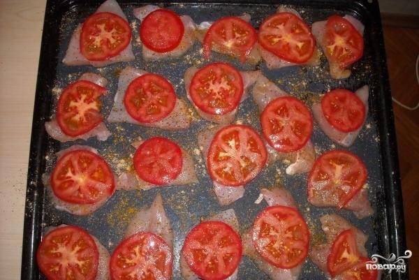 Нарежьте помидоры колечками. Выложите их поверх курицы.