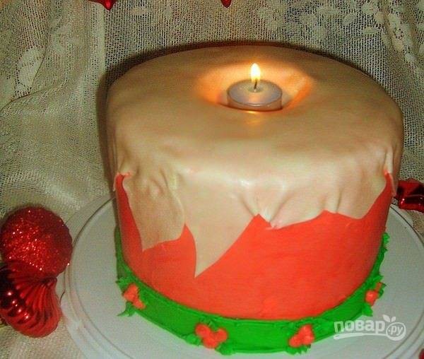 Готовую мастику розового цвета раскатайте, оберните ею торт полностью. Белую мастику уложите сверху в виде потёкшего воска, а зелёную — снизу. Торт готов! Остудите его немного в холодильнике. В середину поставьте свечу.