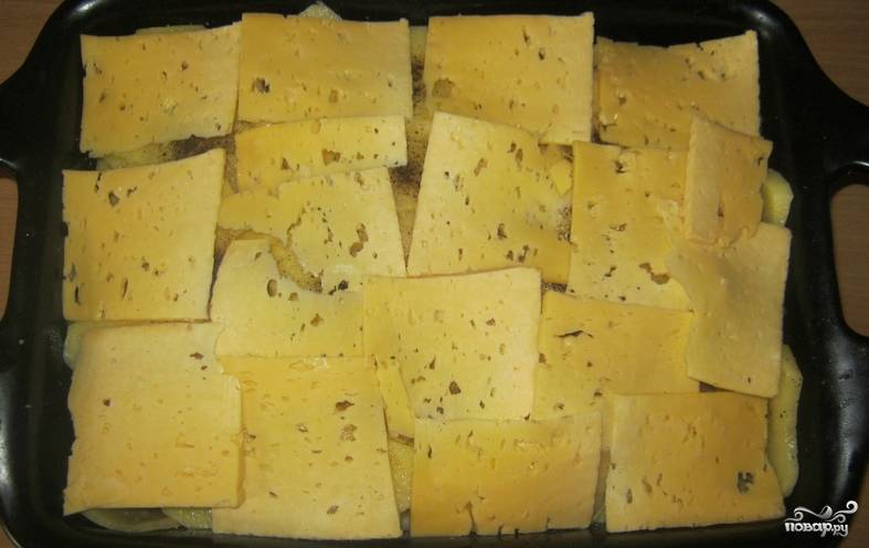Нарезаем тонкими пластинками сыр. Раскладываем его поверх картофеля.