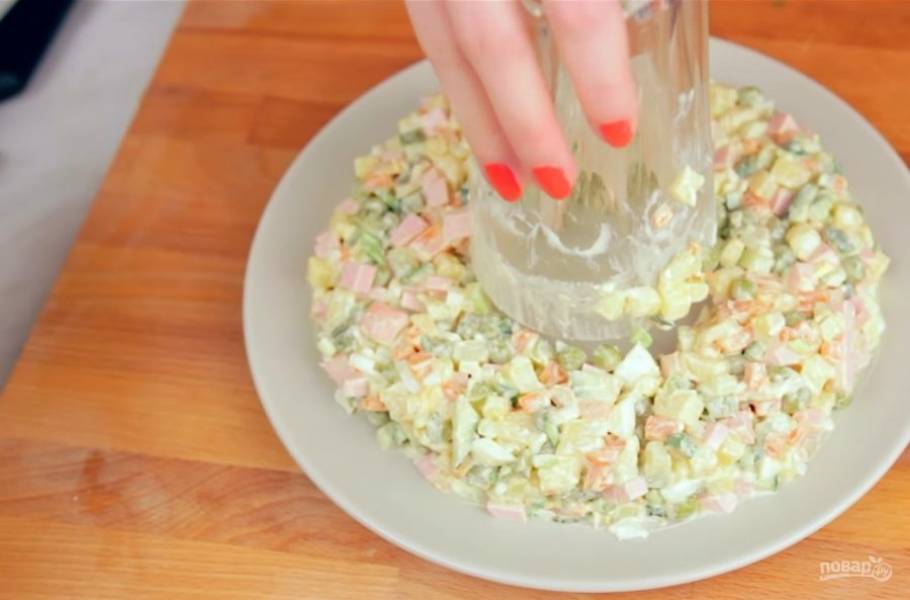 3. Далее сформируйте венок из салата. Для этого в центр тарелки поставьте стакан и выложите вокруг стакана кольцом салат. 