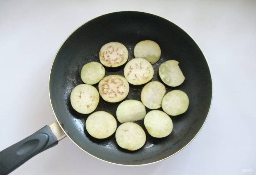 В сковороду налейте подсолнечное масло, нагрейте его и выложите нарезанные баклажаны.