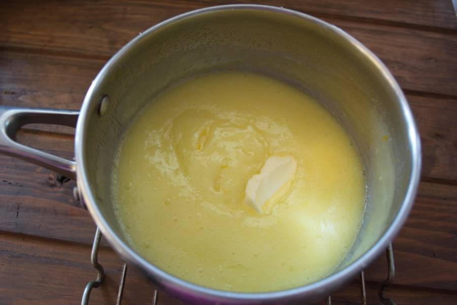 После закипания (постоянно помешивая) варить массу 1 минуту. Выключить. Добавить сливочное масло и снова вымешать. Переложите крем в другую емкость.