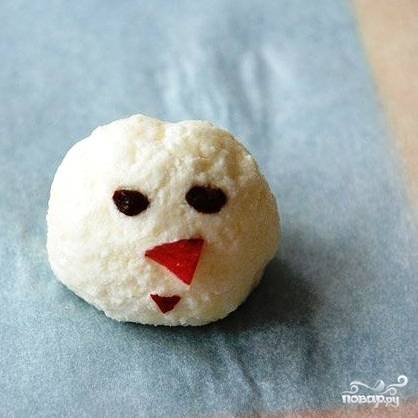 Самый маленький шарик - это голова. Глаза снеговику делаем из изюма, нос - из кусочка яблока.