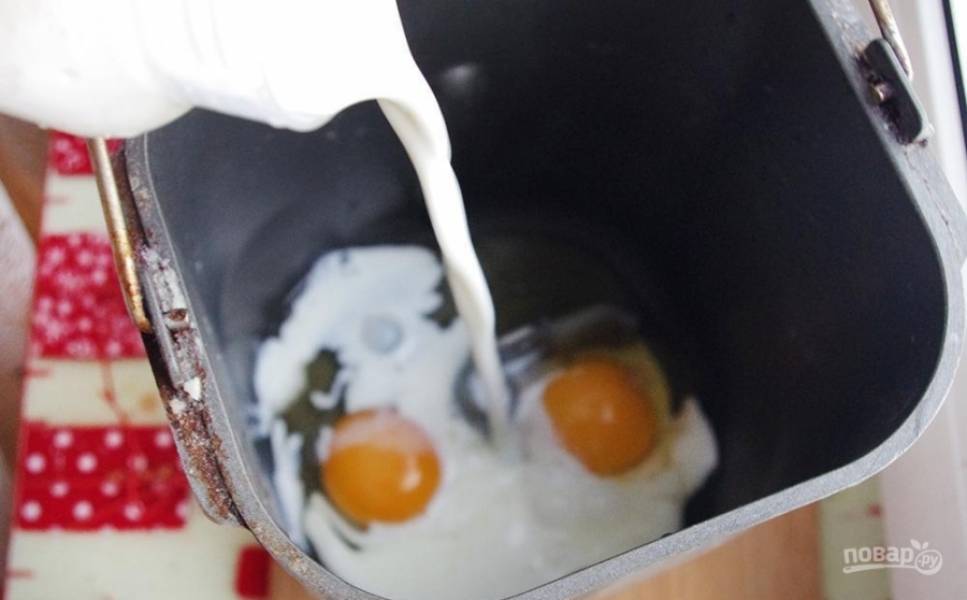 В ведро хлебопечки вбейте 2 яйца и влейте тёплое молоко.