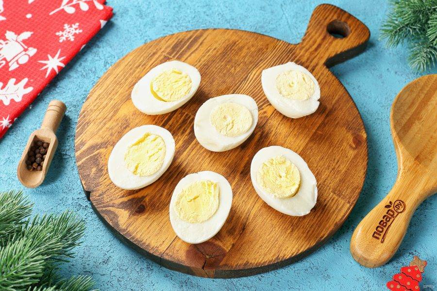Яйца очистите от скорлупы и разрежьте их пополам.